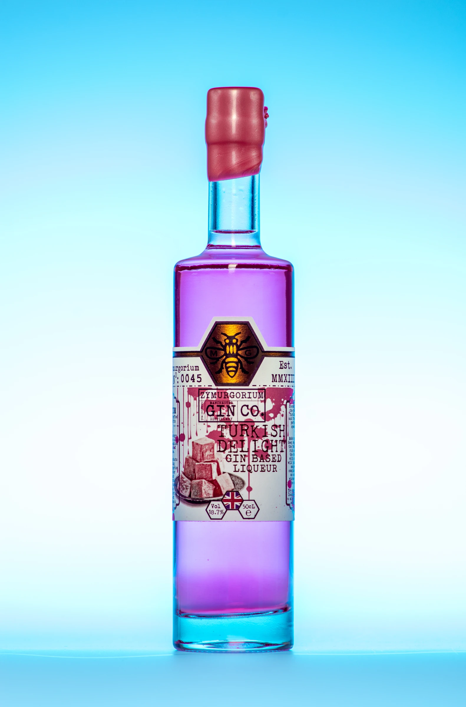 Pink gin liqueur bottle against a blue studio background